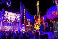 a crowd of people standing around in front of neon signs and buildings at night time