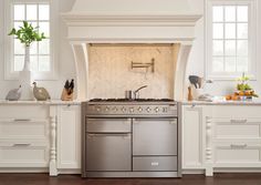 a stove top oven sitting inside of a kitchen next to white cupboards and drawers