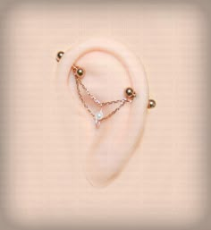 a pair of ear rings with pearls and chains attached to them on a beige background