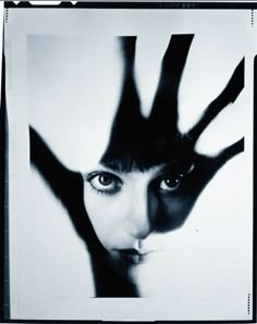 a black and white photo of a woman's face with her hands in the air