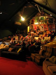 a room full of people sitting on couches in front of a red carpeted floor