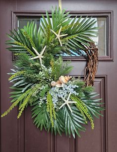 a wreath with starfishs and palm leaves hangs on the front door to welcome guests