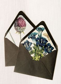 two envelopes with flowers on them sitting next to each other