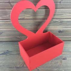 a red heart shaped box sitting on top of a wooden table