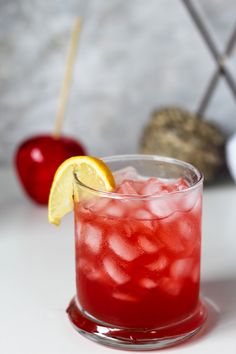 a red drink with ice, lemon and an apple