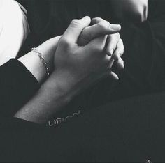 black and white photograph of two people holding each other's hands while sitting on a couch