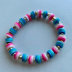 a bracelet with multicolored beads and gold accents on a white surface, close up