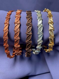 four different types of bracelets sitting on top of a purple cloth covered tablecloth