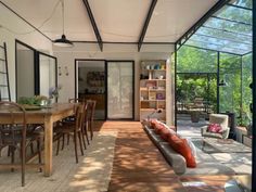 a living room filled with furniture next to a dining table and glass walls covered in windows