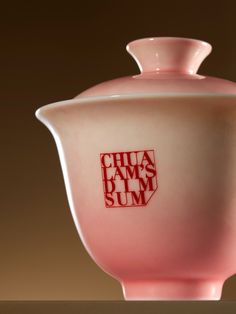 a pink vase sitting on top of a table next to a brown wall with the words chua sams summ printed on it