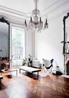 a living room filled with furniture and a chandelier hanging from the ceiling next to a window