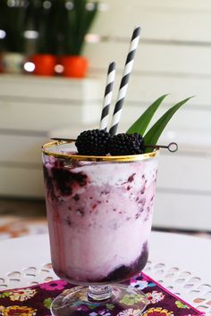 a glass with some blackberries in it and two straws sticking out of the top