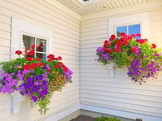 two hanging flower baskets on the side of a house