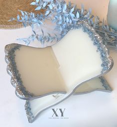 a white and blue tray with silver trimmings next to a straw hat on a table