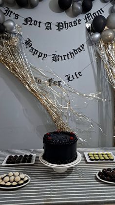 a table topped with cakes and desserts next to balloons