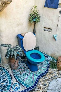 a blue toilet sitting on top of a tiled floor next to a potted plant