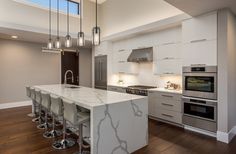 a large kitchen with an island and lots of stools next to the counter top