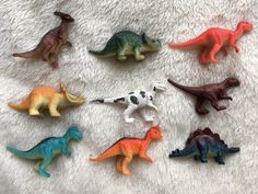 small plastic toy dinosaurs on a white blanket