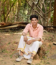 a young man sitting on top of a rock in the middle of a wooded area