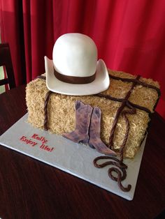 a cake made to look like a cowboy's hat and boots on top of hay