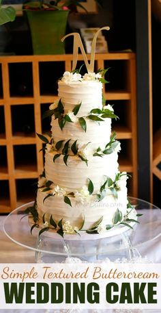 a simple layered buttercream wedding cake with greenery