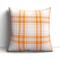 an orange and white plaid pillow on a white wall