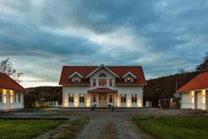 a white house with red roof and lights on it's windows is lit up in the evening