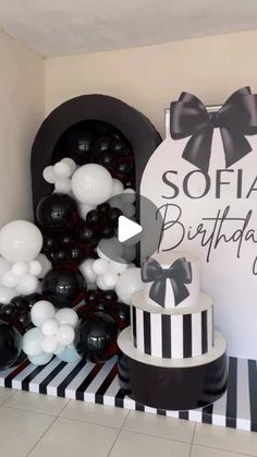 a black and white birthday party with balloons, cake and balloon arch in the corner