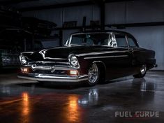 an old black car parked in a garage