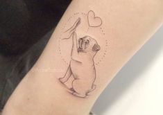 a woman's arm with a small tattoo of a dog holding a heart