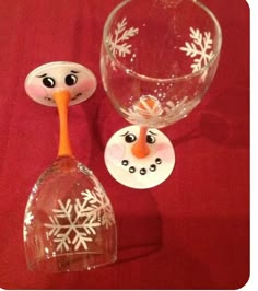 two wine glasses sitting next to each other on a red tablecloth with snowflakes