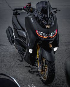 a black motorcycle parked on top of a street next to a parking lot with no people