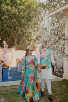 a man and woman dressed in colorful clothing are standing outside with soap bubbles coming out of their mouths