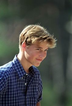 a close up of a person wearing a plaid shirt and looking at the camera with a smile on his face