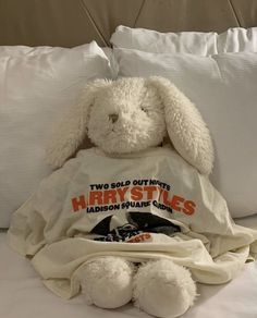 a white stuffed animal sitting on top of a bed