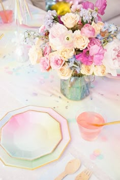 a vase filled with pink and white flowers on top of a table next to utensils