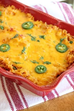 a casserole dish with cheese, green peppers and sauce in it on a table