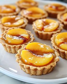 several small desserts on a white plate with some peaches in the top half