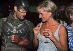 two people dressed up as batman and robin wayne at a costume party, one holding a wine glass while the other looks on