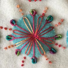 a close up of a piece of art made out of yarn and knitting needles with beads