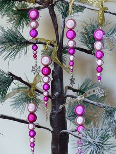 a christmas tree decorated with pink pearls and gold ornaments in front of a white wall