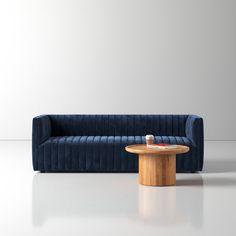 a blue velvet couch and table in front of a white wall with light reflection on the floor