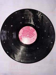 an old record with pink and white disco ball on it's side, sitting on a table