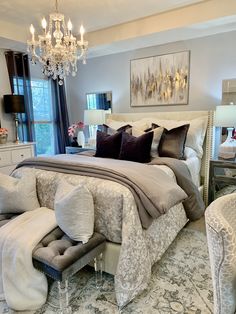 a bedroom with a large bed, chandelier and two chairs in front of it