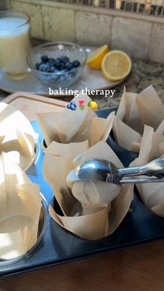 a muffin tin with blueberries, lemons and milk in it sitting on a counter