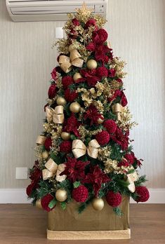 a christmas tree decorated with red and gold ornaments in front of a wall mounted air conditioner