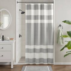 a bathroom with a shower curtain, mirror and rug on the floor in front of it