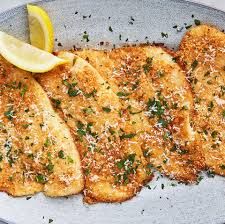 three pieces of fried fish on a plate with lemon wedges and parmesan cheese