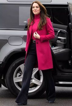 a woman in a pink coat and black pants