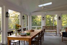 a wooden table sitting on top of a hard wood floored porch next to windows